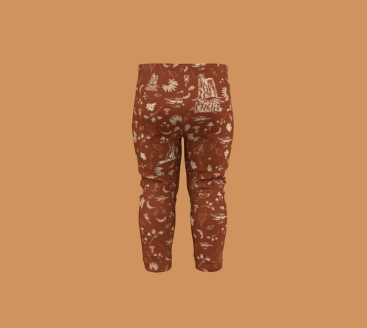 Orange baby leggings with light coloured forest motifs.