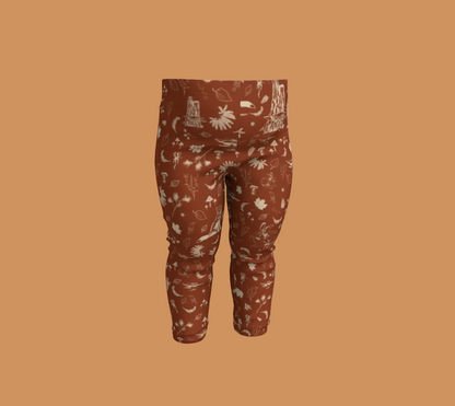 Orange baby leggings with light coloured forest motifs.