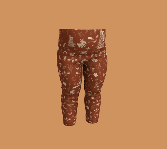 Orange baby leggings with light coloured forest motifs.