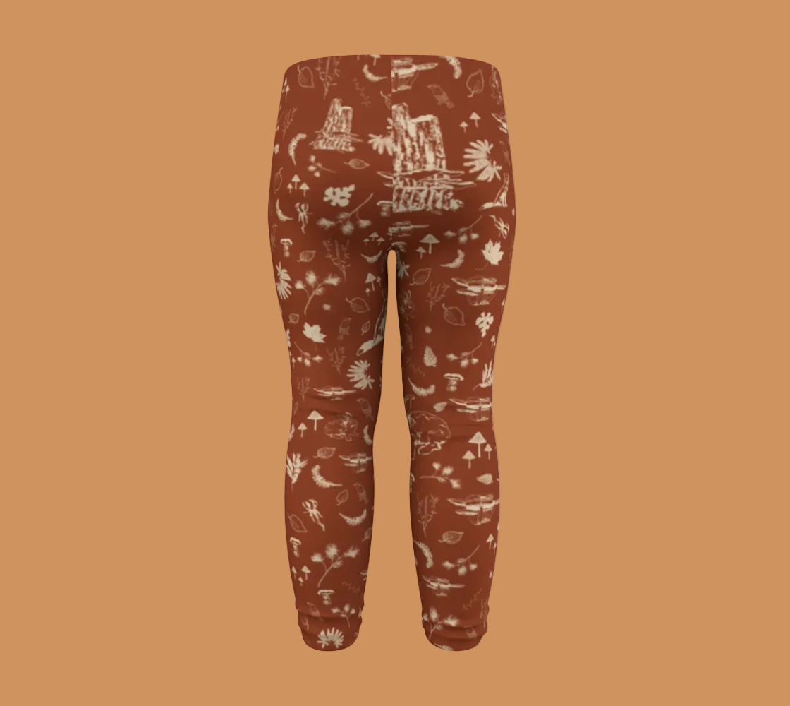 Orange baby leggings with light coloured forest motifs.