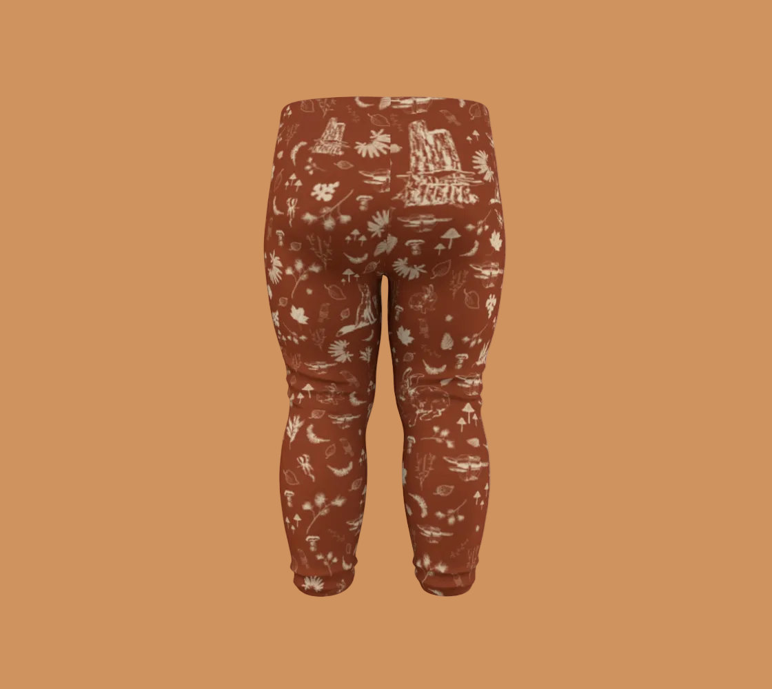 Orange baby leggings with light coloured forest motifs.