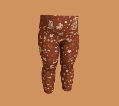 Orange baby leggings with light coloured forest motifs.