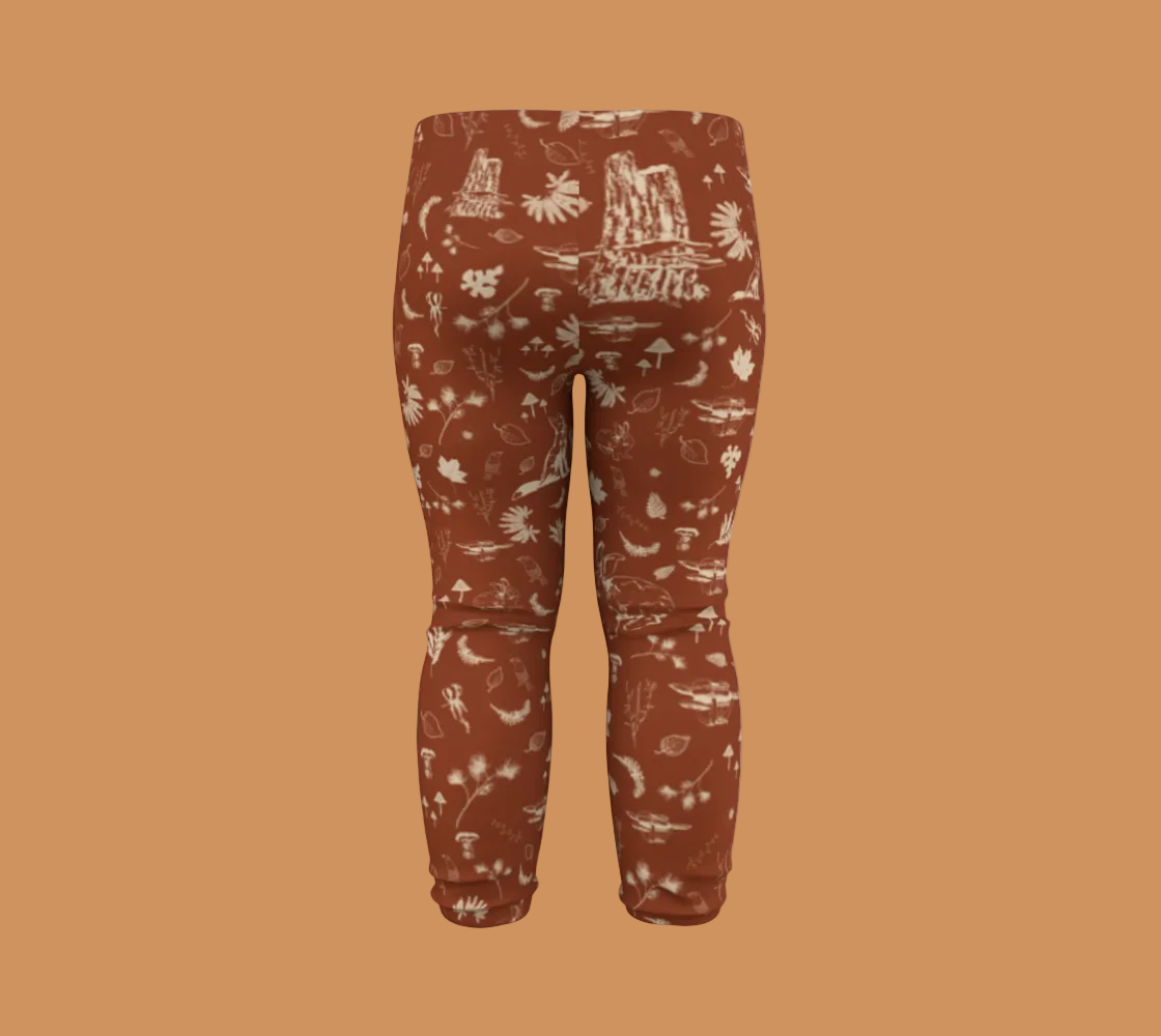 Orange baby leggings with light coloured forest motifs.